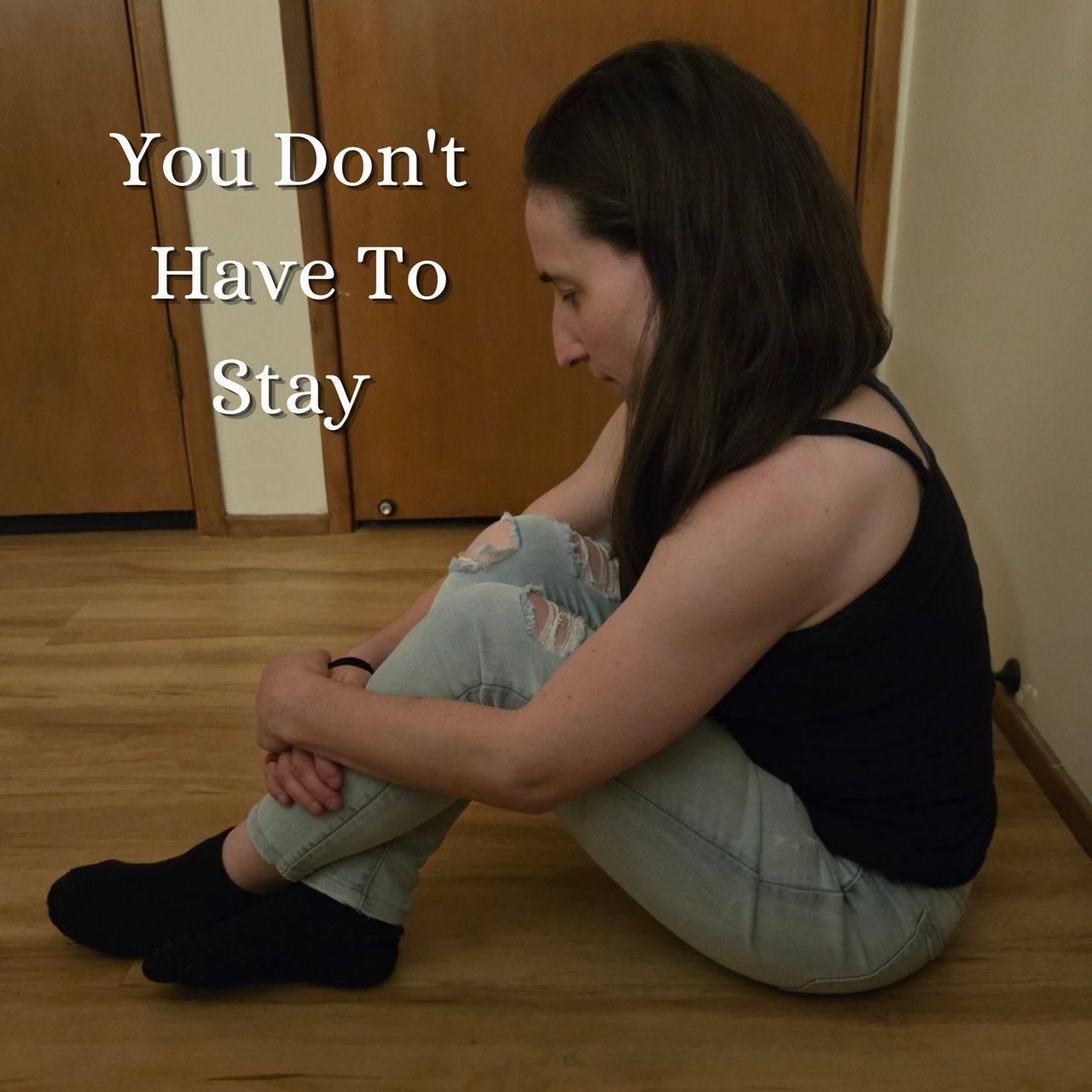Woman sitting on floor, head resting on knees